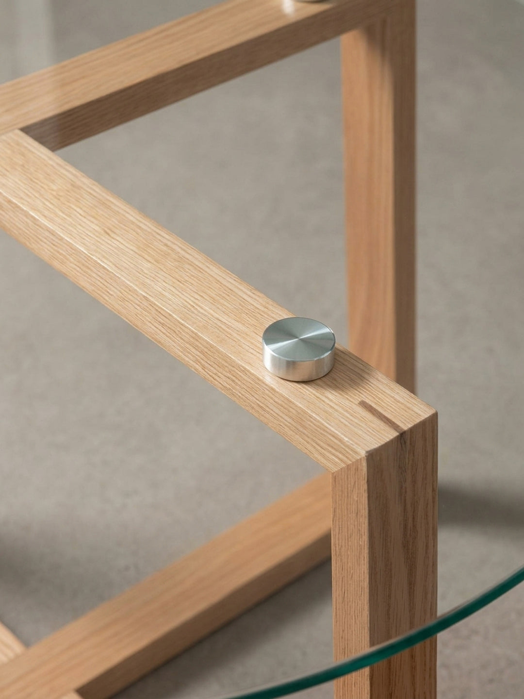 Makroaufnahme eines der polierten Metall-Abstandshalter, der die Glasplatte sicher auf dem massiven Eichenholzrahmen des Stubentisches fixiert._