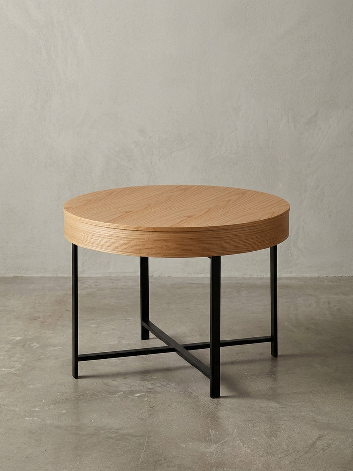 Freigestellter Design Couchtisch mit Eichenfurnier und schwarzem Metallgestell, runde Form, frontale Ansicht auf weißem Hintergrund._