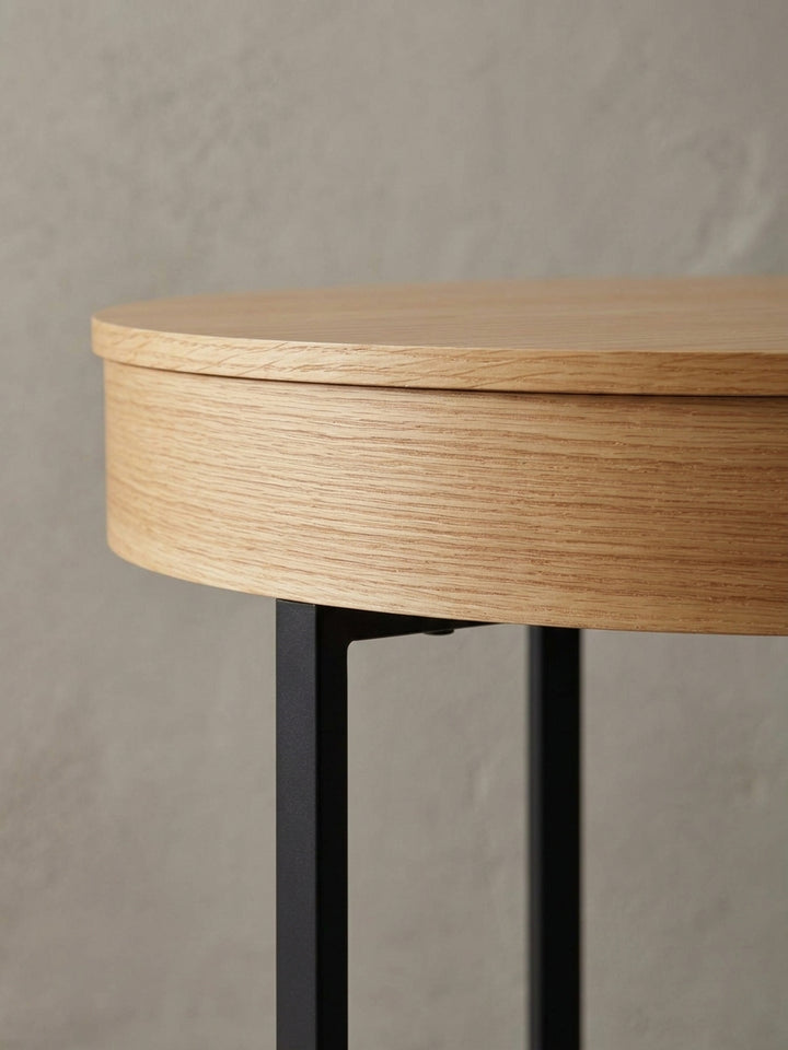 Detailaufnahme des Übergangs von der Eichenfurnier-Tischplatte zum mattschwarzen Stahlbein, die den Materialmix des modernen Lounge-Tisches betont._