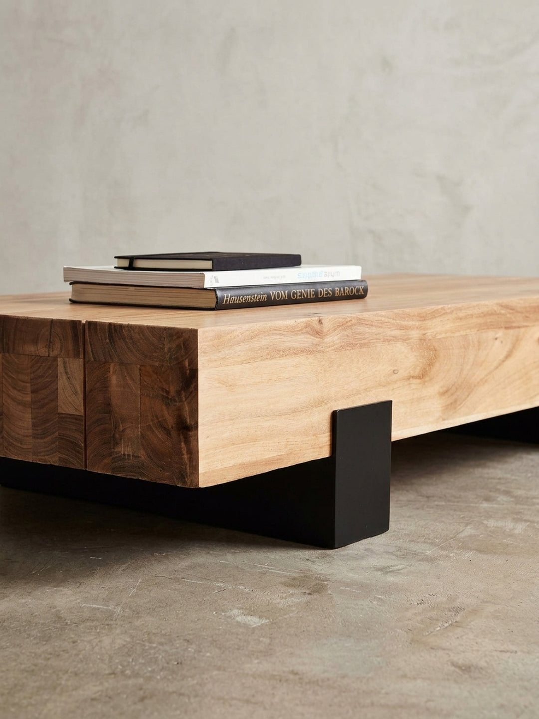 Makroaufnahme der Verbindung zwischen Akazienholzplatte und schwarzem Metallbein. Der feine Materialmix des Designer-Couchtisches zeigt handwerkliche Präzision und robuste Stabilität._