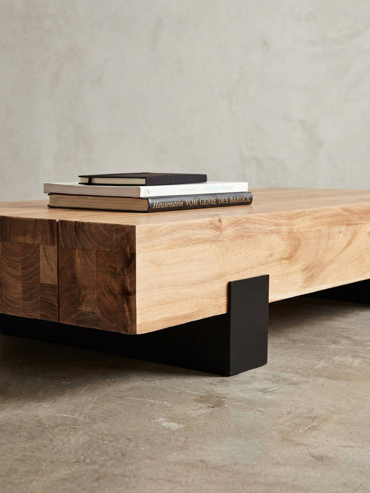 Makroaufnahme der Verbindung zwischen Akazienholzplatte und schwarzem Metallbein. Der feine Materialmix des Designer-Couchtisches zeigt handwerkliche Präzision und robuste Stabilität._