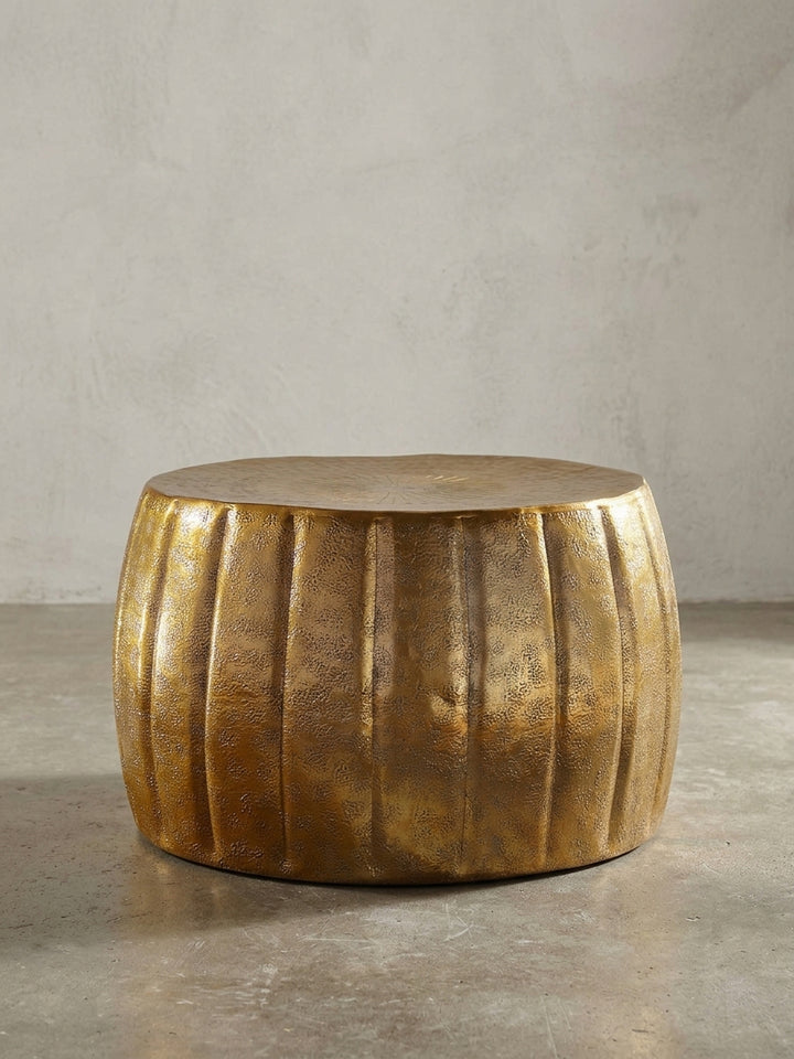 Freigestellter runder Couchtisch in Gold aus Aluminium. Die Frontalansicht zeigt die bauchige Silhouette und die markante vertikale Rillenstruktur des 36 cm hohen modernen Wohnzimmertisches._