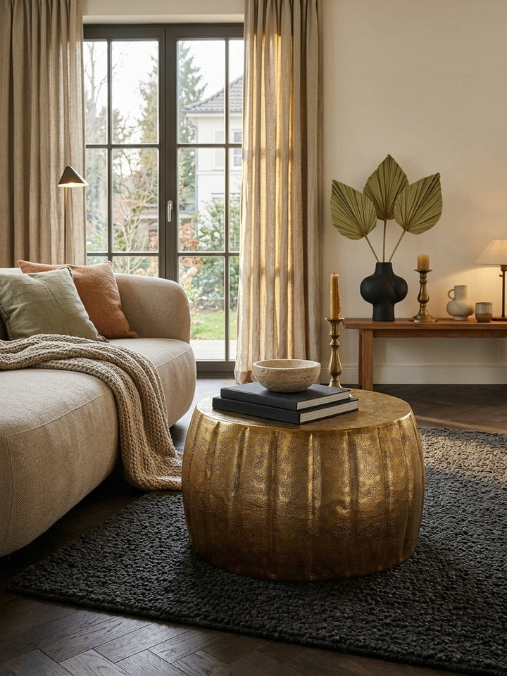 Aufsicht auf den runden Loungetisch in Gold, platziert auf einem dunklen Bouclé-Teppich. Der flache Sofatisch aus Metall zeigt präzise handgefertigte Rillen und eine strahlenförmige Ablage._