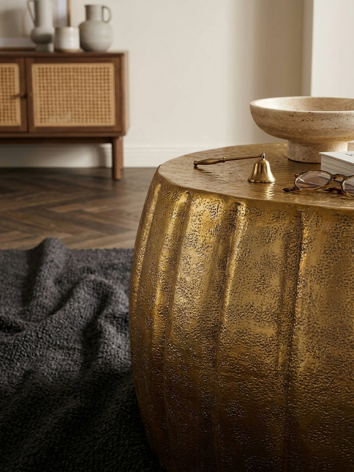 Makroaufnahme der gehämmerten Materialstruktur des goldenen Beistelltisches. Das lackierte Aluminium reflektiert das Licht und betont das orientalische Design des kleinen Stubentisches._
