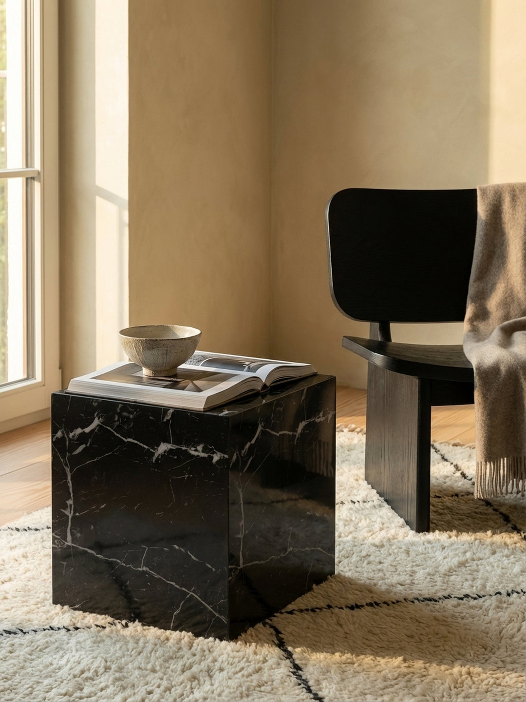 Ein Buch und ein Wasserglas stehen auf dem quadratischen Sofatisch, der eine gemütliche Leseecke am Fenster schafft._