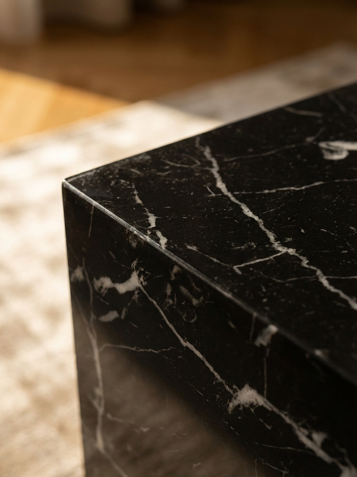 Detailaufnahme der hochglänzenden Oberfläche des schwarzen Couchtischs, die feine Marmor-Maserung und Lichtreflexe zeigt._