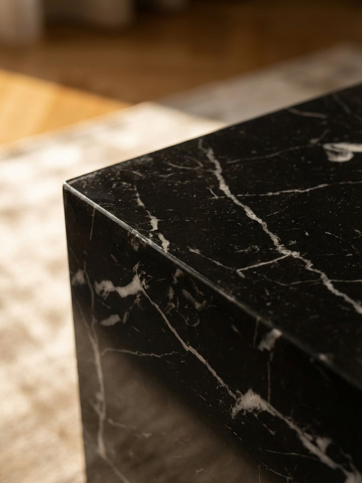 Detailaufnahme der hochglänzenden Oberfläche des schwarzen Couchtischs, die feine Marmor-Maserung und Lichtreflexe zeigt._