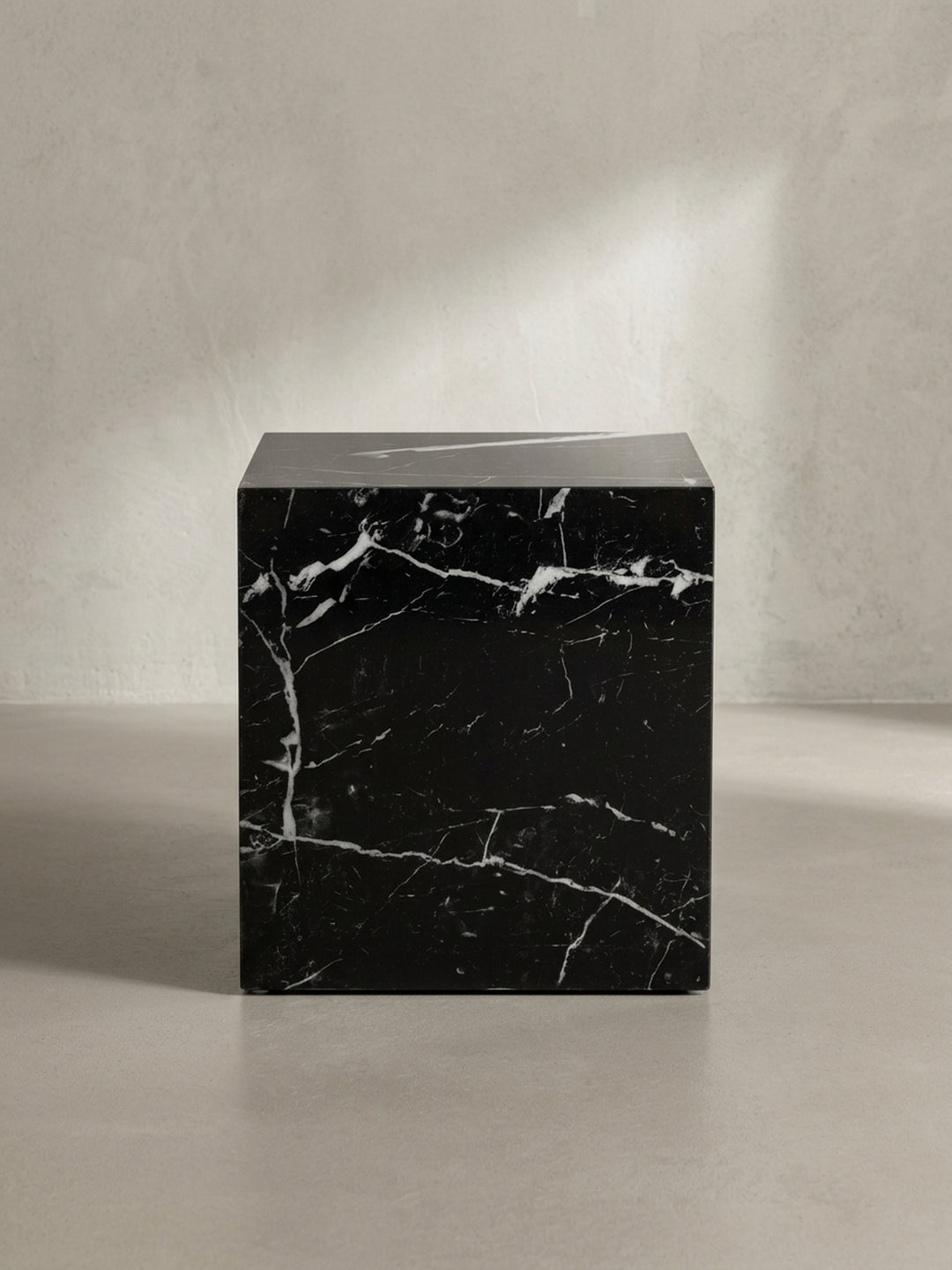 Seitenansicht des 45 cm hohen Beistelltischs, der seine schlanke und blockartige Silhouette in Marmoroptik präsentiert._