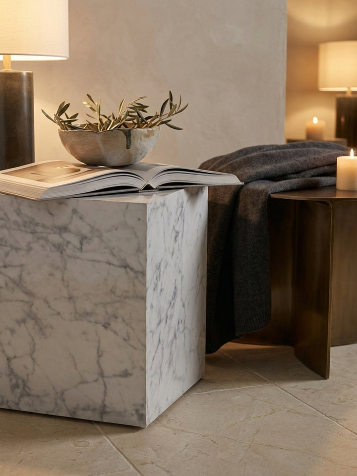 Weißer Monobloc Sofatisch dekoriert mit einem dicken Bildband und Kristallglas im minimalistischen Wohnbereich._