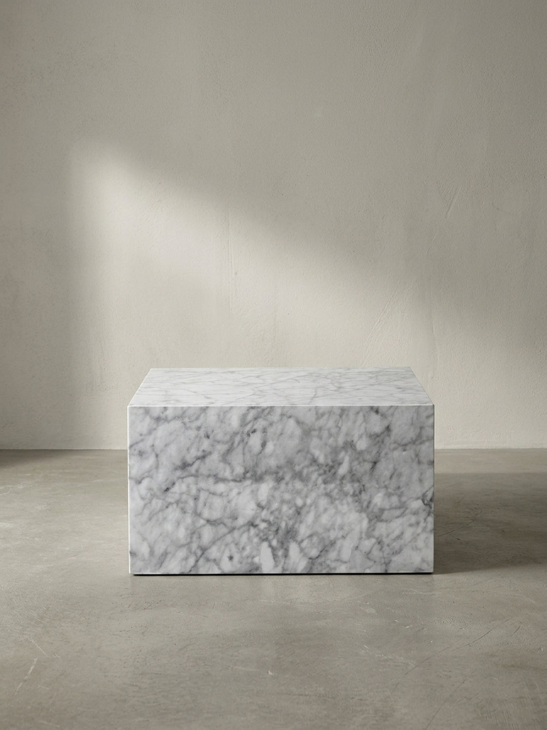 Seitenansicht des 30 cm niedrigen Lounge-Tisches im Monolithen-Stil, dessen weiße Stein-Imitation durch die hochglänzende Versiegelung eine besonders realistische Tiefe und luxuriöse Ausstrahlung erhält._
