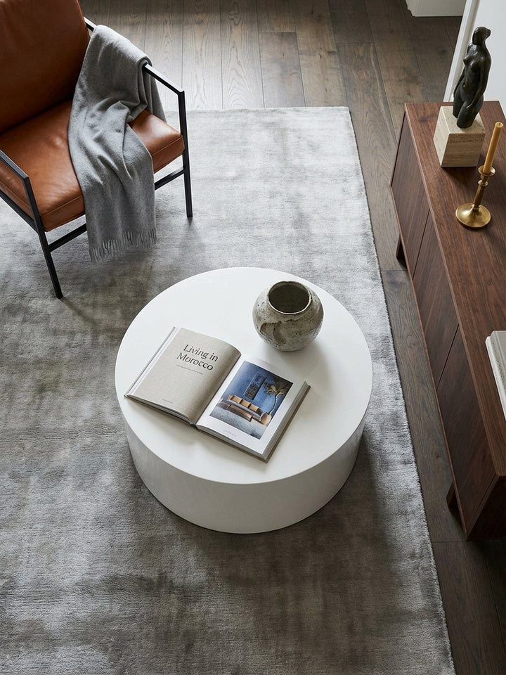 Draufsicht auf den runden Design-Couchtisch mit 60 cm Durchmesser, arrangiert mit einem Schachspiel auf einem modernen, grauen Teppich._