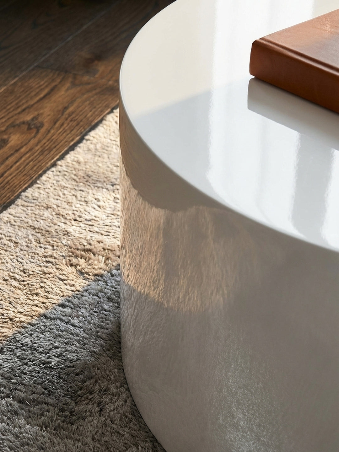 Makroaufnahme der spiegelglatten Hochglanz-Oberfläche des weißen Couchtischs, die das Licht sanft reflektiert und makellos verarbeitet ist._