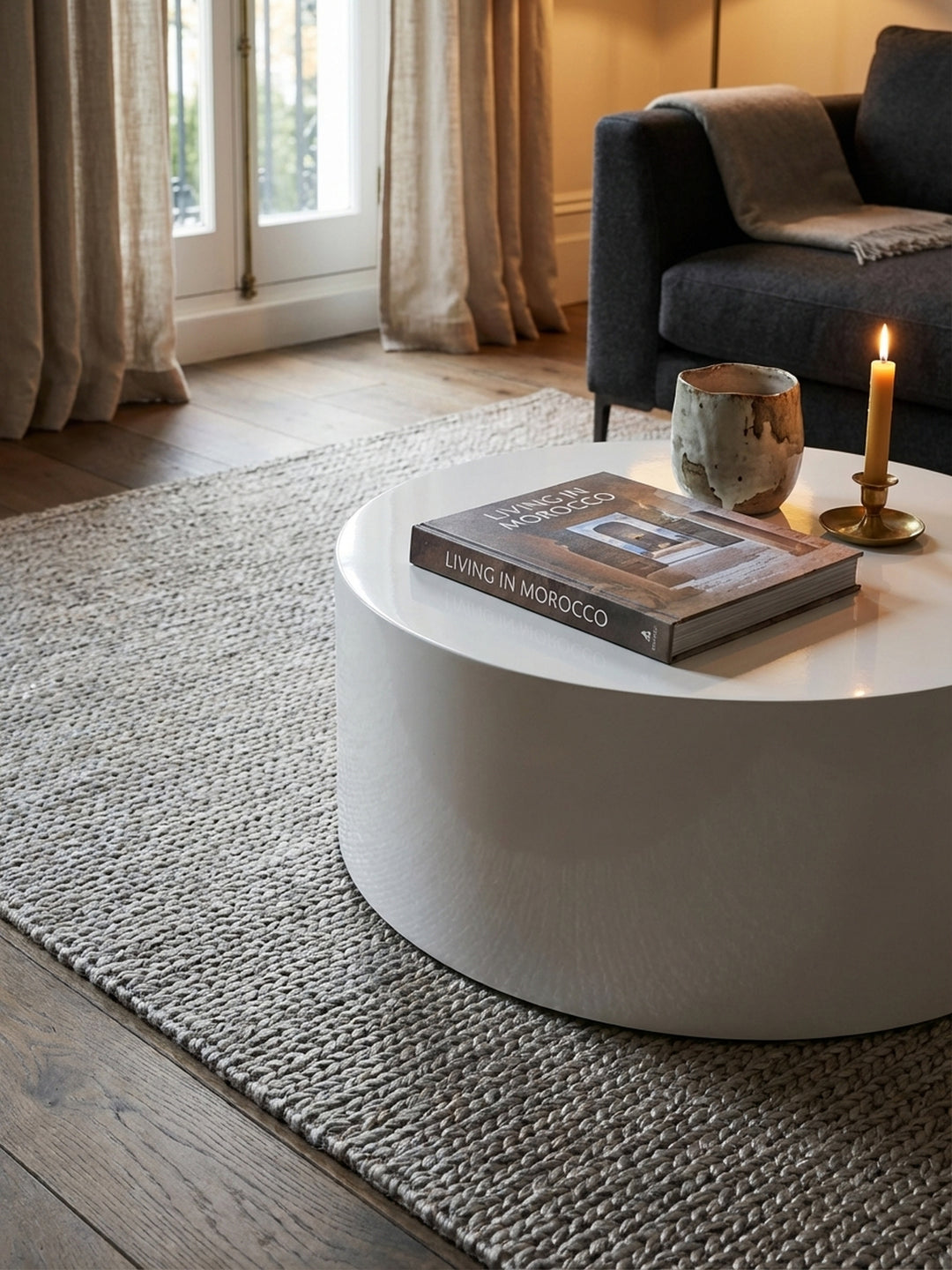 Detailansicht des weißen Sofatisches mit einem Design-Schachspiel aus Holz und einem schwarzen Dekoelement, das eine stilvolle Vignette bildet._