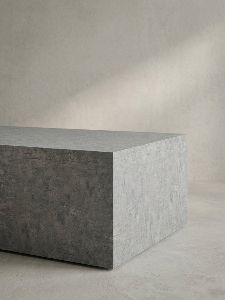 Detaillierter Blick auf die nahtlos verarbeiteten Ecken des grauen Sofatisches mit matter Beton-Struktur._