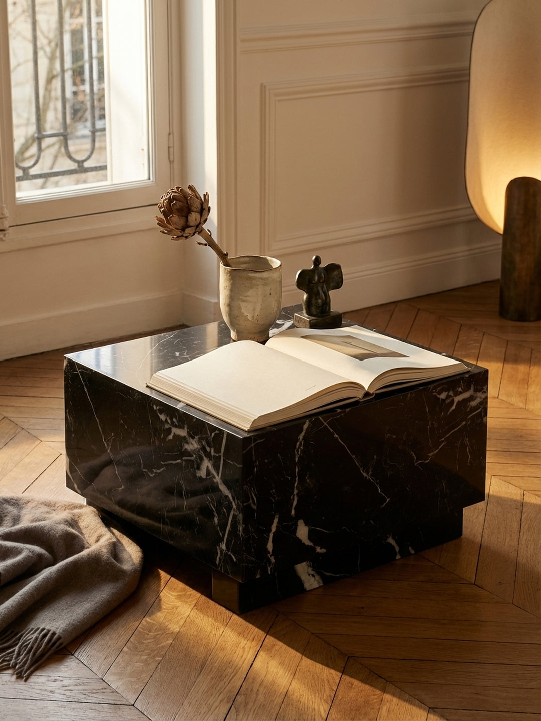 Ein Design-Couchtisch in Würfel-Form mit einem aufgeschlagenen Buch und einem Glas Wasser, eine stille Leseecke im Wohnzimmer schaffend._