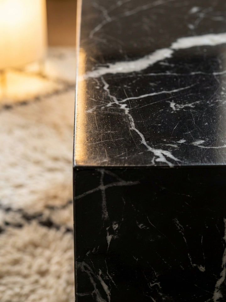 Makroaufnahme der hochglänzenden Oberfläche des Sofatisches, die die feine weiße Marmorierung auf dem schwarzen Grund detailreich zeigt._