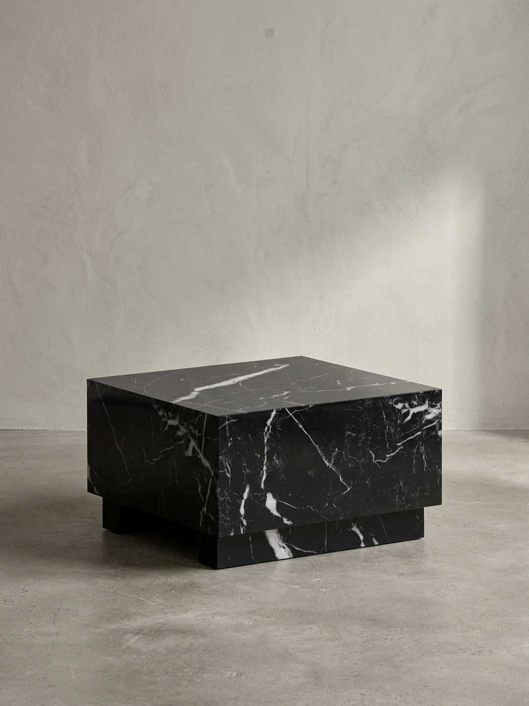 Frontansicht des monolithischen Couchtisches MONOBLOC 60x60cm in glänzendem Schwarz mit weißer Marmor-Maserung, freigestellt._