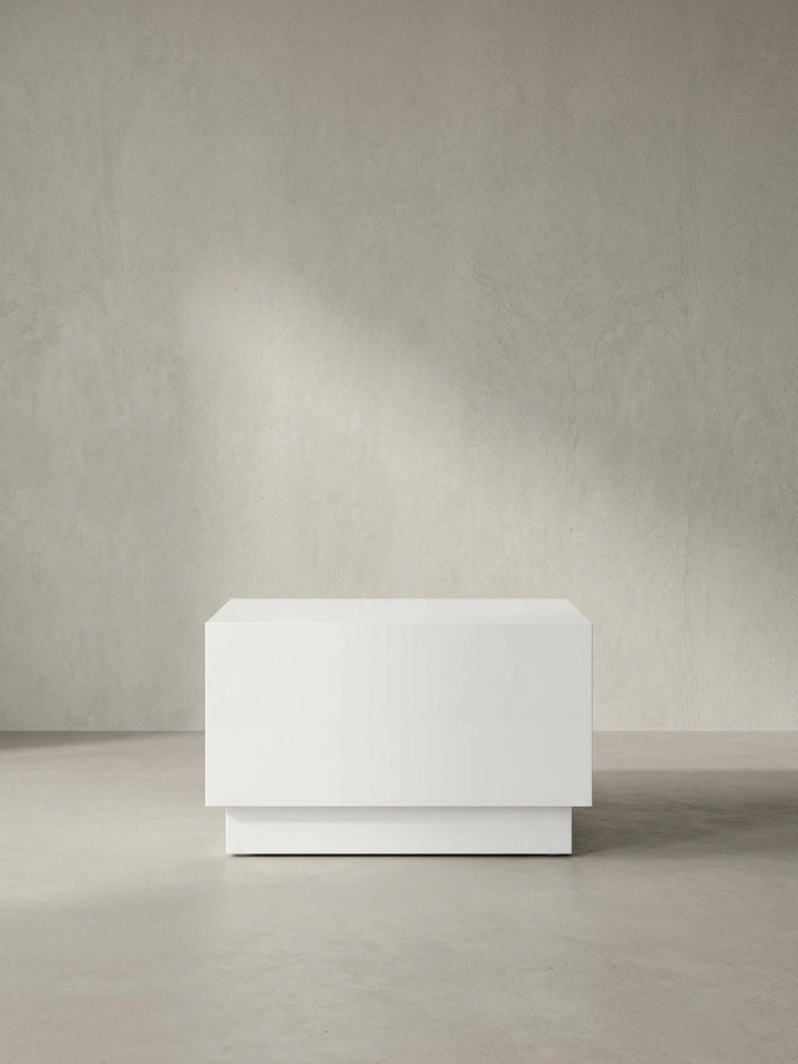 Weißer Sofatisch in Würfel-Form 60x60x35 cm mit Hochglanz-Lackierung im Seitenprofil auf neutralem Hintergrund._