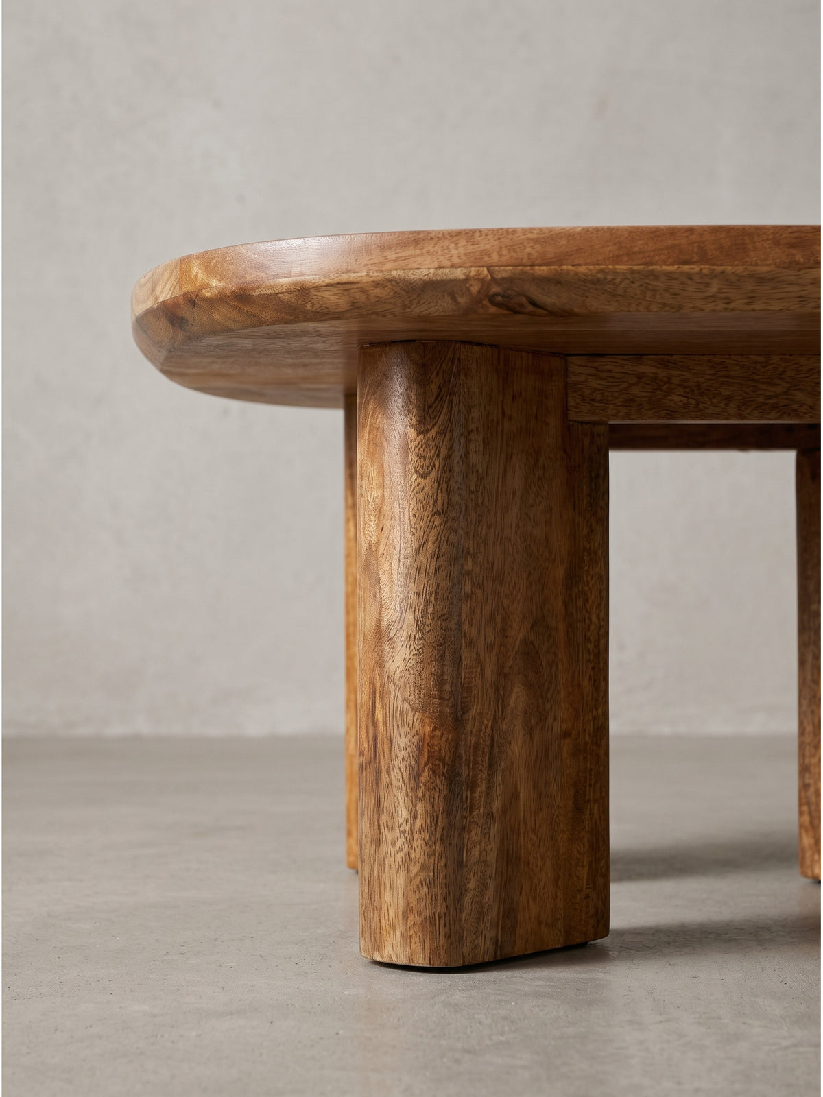 Gesamtansicht des modernen Massivholz Couchtisches in warmen Naturtönen besticht durch skulpturales Design und lebendige Maserung des Naturholzes.