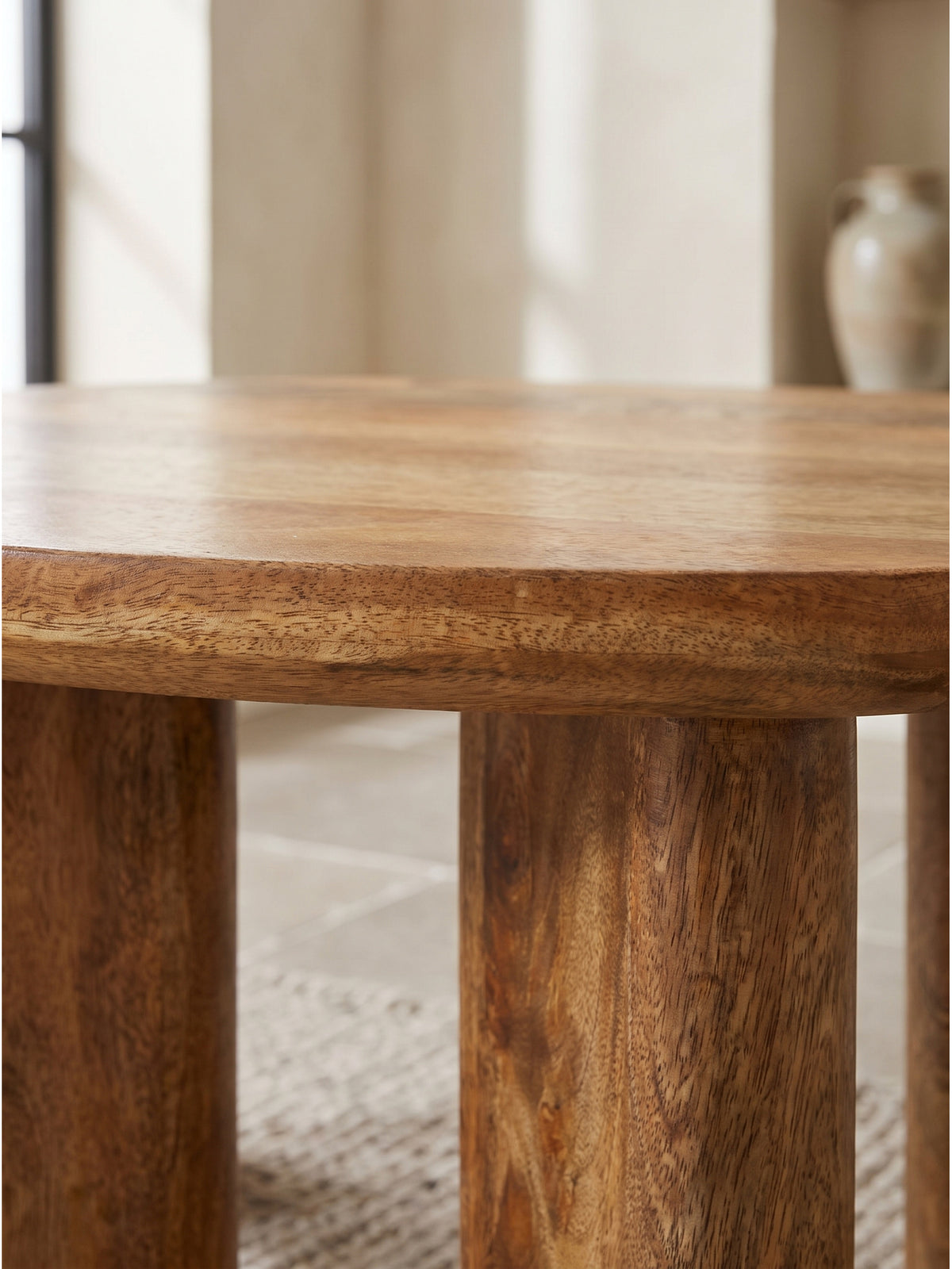 Nahaufnahme der lebendigen Holzmaserung des Mango Couchtisches, die warme honigfarbene Lackierung reflektiert sanftes Tageslicht im organischen Interior._