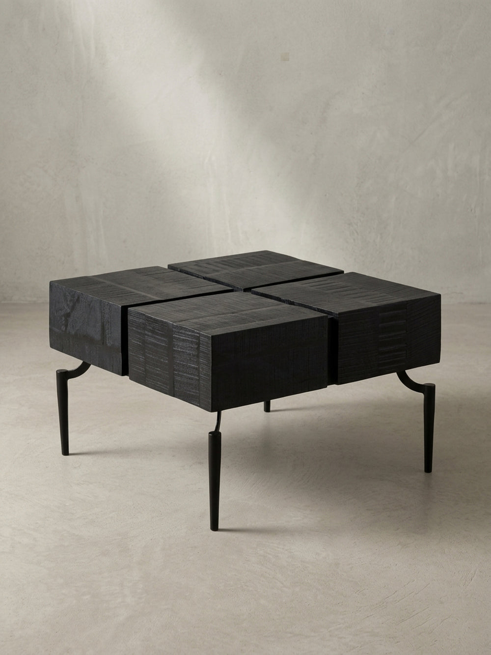 Schräge 3/4-Ansicht des schwarzen Cube-Couchtischs, die die Tiefe der viergeteilten Tischplatte und die filigranen Metallbeine zeigt._