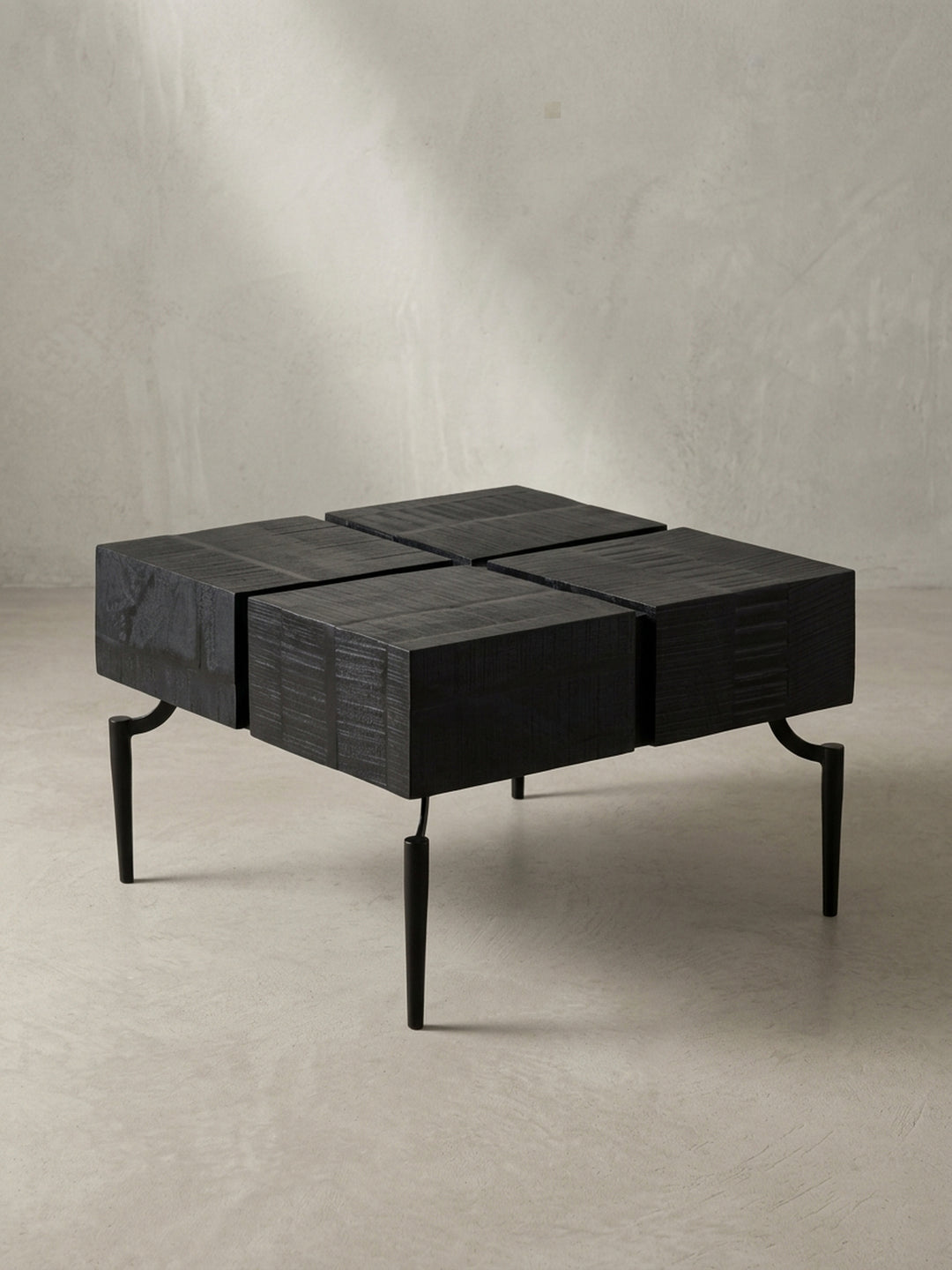 Schräge 3/4-Ansicht des schwarzen Cube-Couchtischs, die die Tiefe der viergeteilten Tischplatte und die filigranen Metallbeine zeigt._