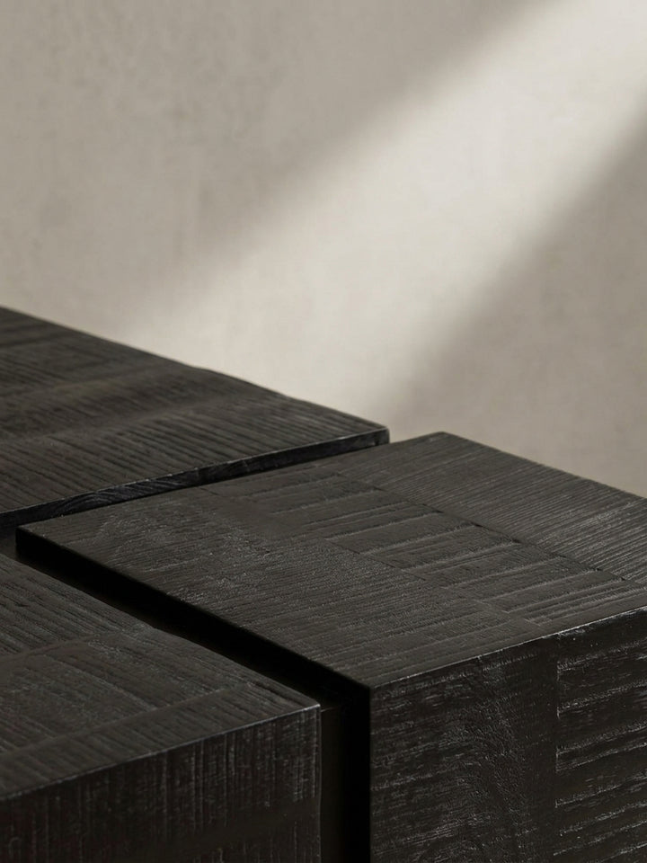 Perspektivische Ansicht des schwarzen Couchtischs, die das Zusammenspiel der massiven Holzplatte und der leichten Beine betont._