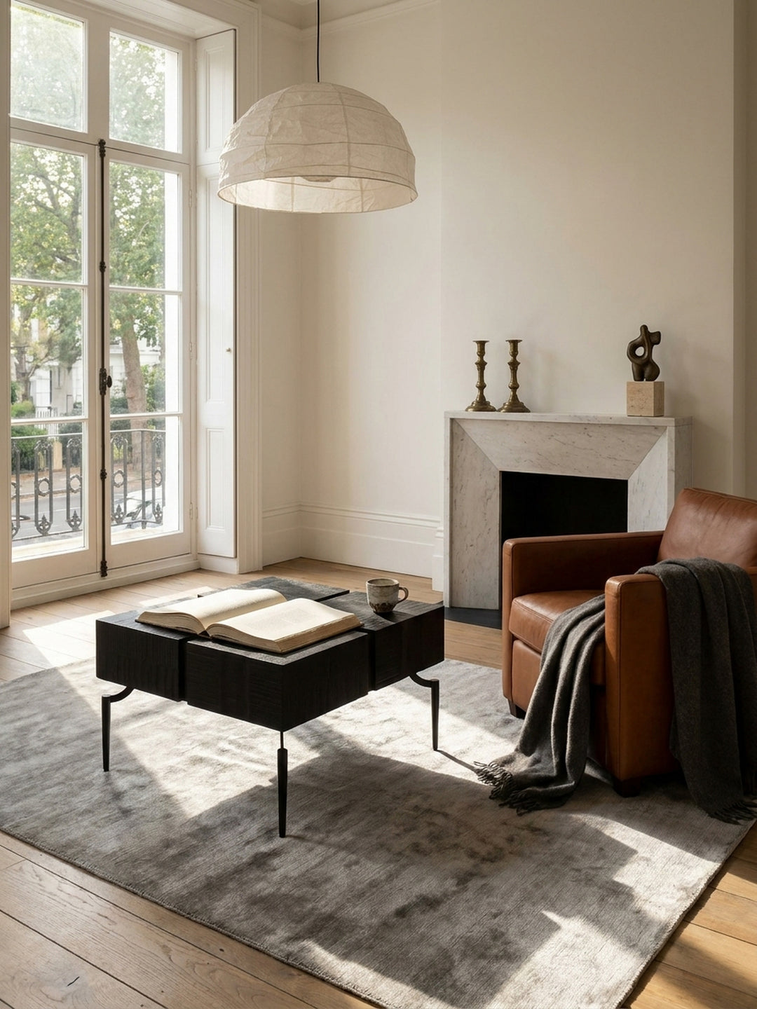 Quadratischer Couchtisch aus schwarzem Mangoholz im Mittelpunkt eines hellen Wohnzimmers mit beigem Sofa und Wollteppich._