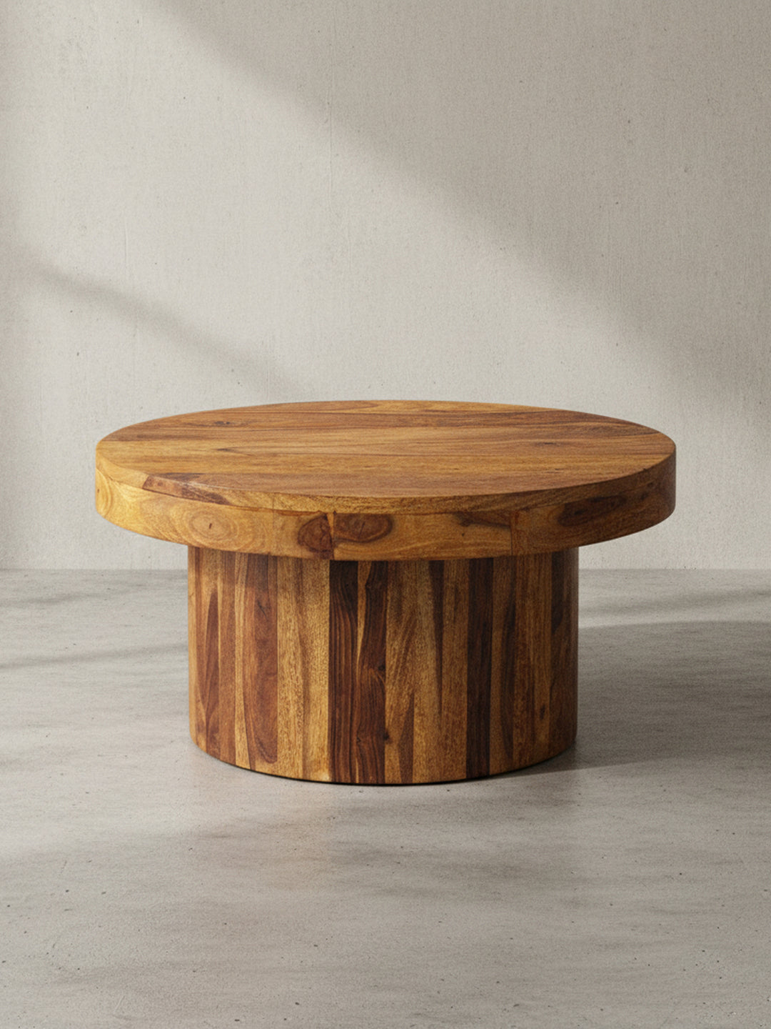 Gesamtansicht des massiven runden Couchtisches, der durch sein minimalistisches Design und das ausdrucksstarke Sheesham-Holz als zeitloses Möbelstück wirkt._