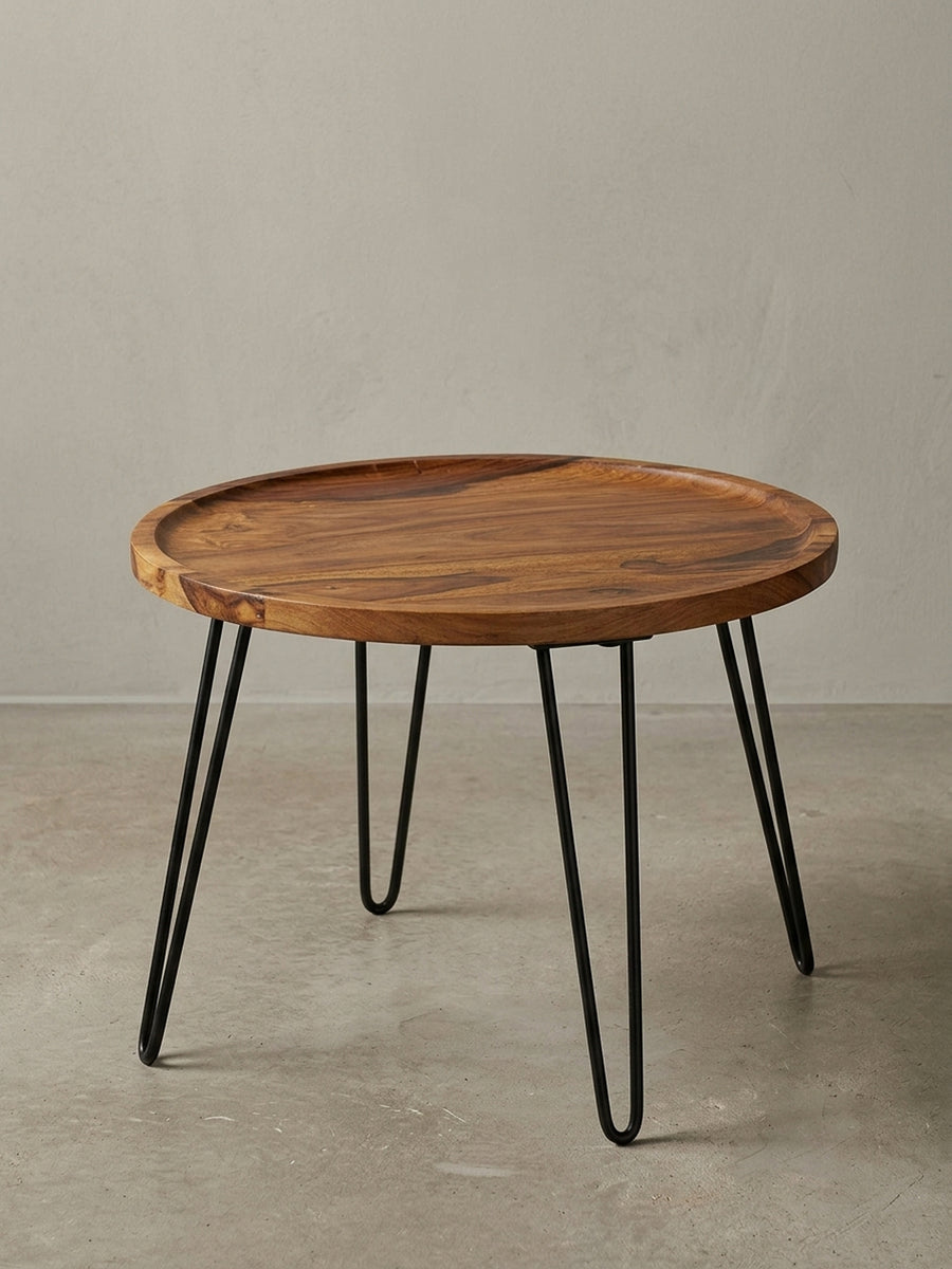 Moderner Wohnzimmertisch rund mit 60cm Durchmesser vor weißem Hintergrund. Die Kombination aus brauner Massivholzplatte und drei schwarzen Metallbeinen wirkt filigran._