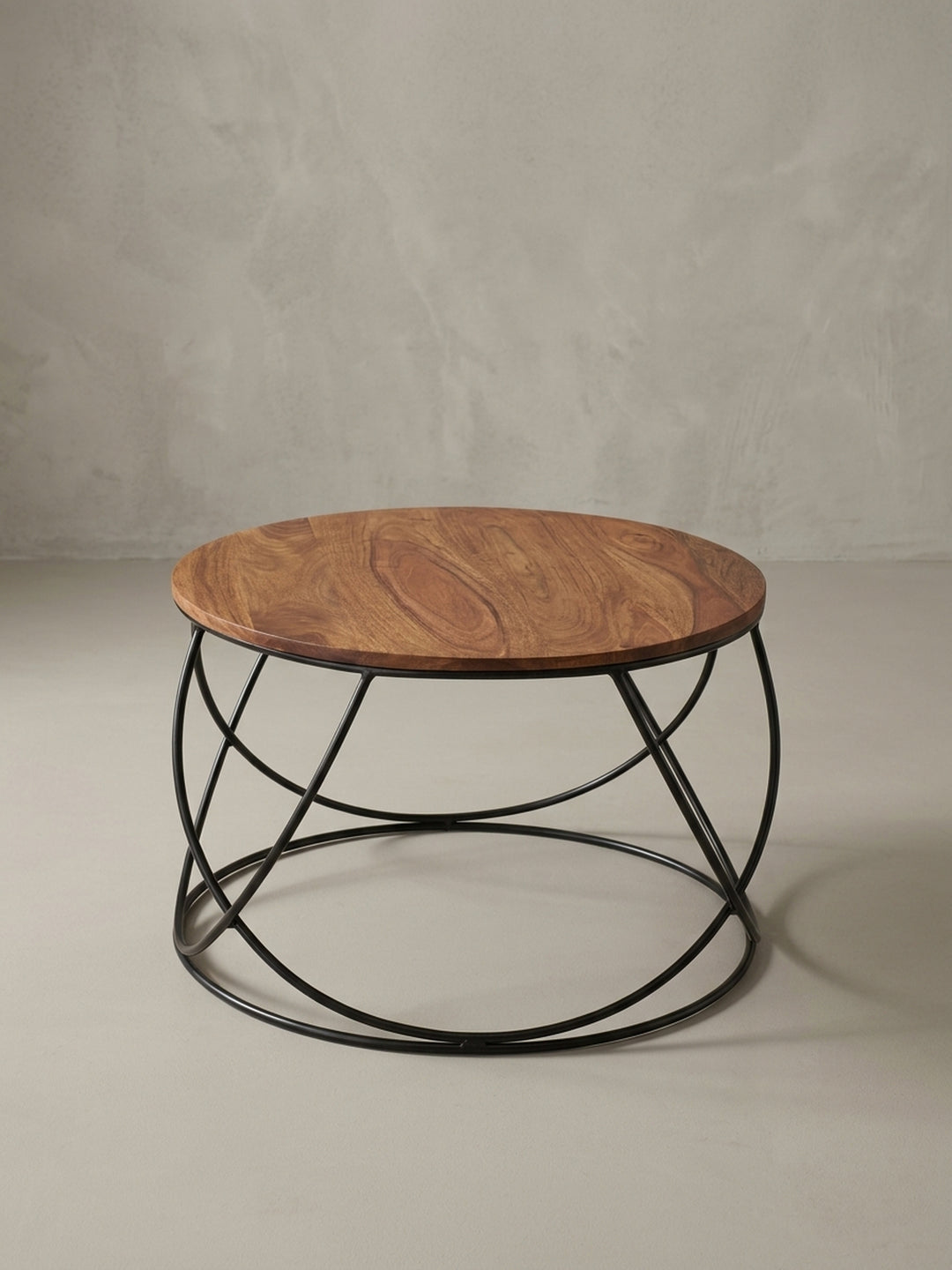 Dreiviertelansicht des Sofatischs im Industrial-Design, der das Zusammenspiel von der warmen Holzplatte und dem skulpturalen, korbförmigen Metallgestell betont._
