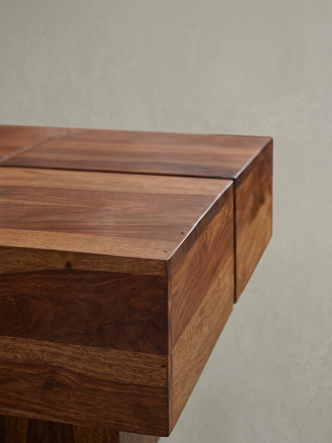 Nahaufnahme einer Ecke des massiven Couchtisches, die die saubere Kantenverarbeitung und die schützende Klarlack-Veredelung des Sheesham-Holzes zeigt._