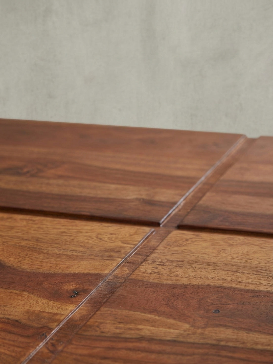 Perspektivische Ansicht des Holztisches für das Wohnzimmer, die die optische Tiefe der vierquadratigen Tischplatte und des Sockels betont._