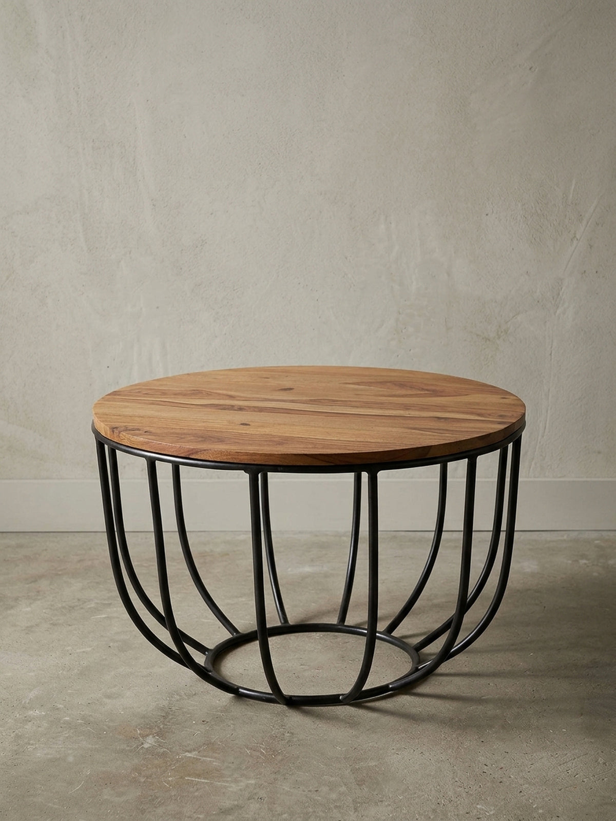Runder Sofatisch im angesagten Industrial Design freigestellt. Der Materialmix aus warmem Massivholz in Braun und dem korbartigen schwarzen Metallgestell wirkt leicht und modern.