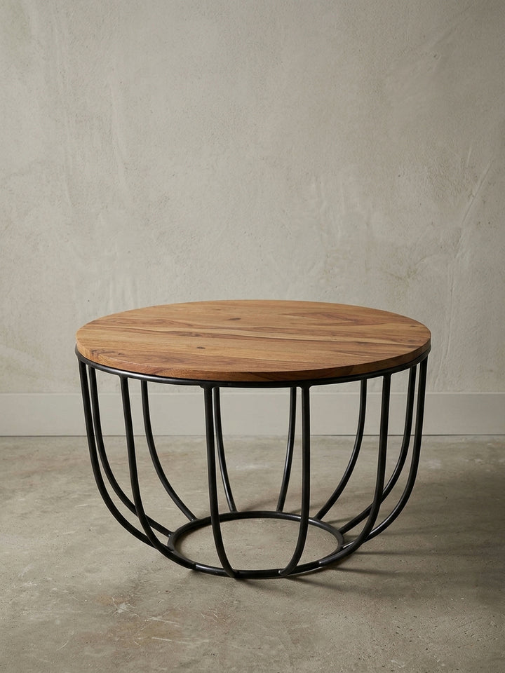 Runder Sofatisch im angesagten Industrial Design freigestellt. Der Materialmix aus warmem Massivholz in Braun und dem korbartigen schwarzen Metallgestell wirkt leicht und modern._