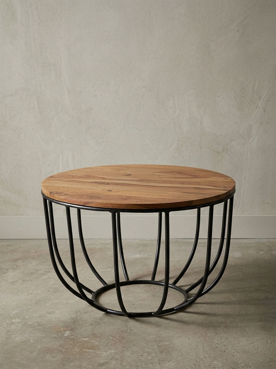 Runder Sofatisch im angesagten Industrial Design freigestellt. Der Materialmix aus warmem Massivholz in Braun und dem korbartigen schwarzen Metallgestell wirkt leicht und modern._