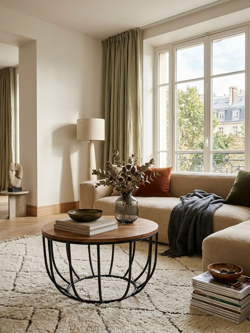 Runder Couchtisch aus Sheesham Massivholz und schwarzem Metall in einem eleganten Wohnzimmer. Der offene Korbtisch setzt warme Akzente im stilvollen Organic-Modern Interior Design._