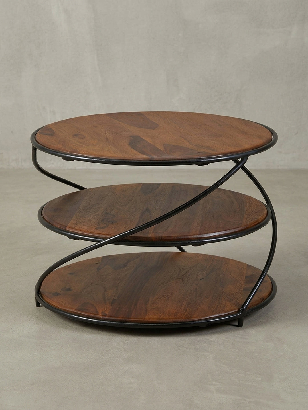 Design-Couchtisch in 3/4-Ansicht, die gedrehte, spiralförmige Struktur des schwarzen Metallrahmens und die runden Holzplatten zeigend._