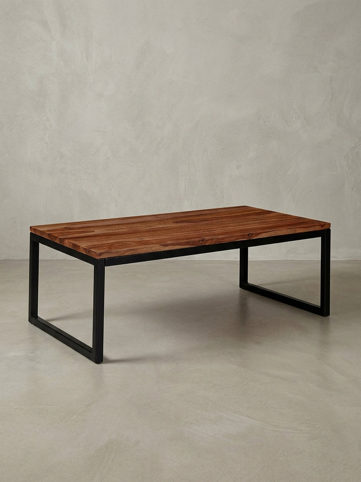Freigestellter Couchtisch im Industrial Design mit Tischplatte aus massivem Sheesham-Holz und schwarzen Metallbeinen, Frontalansicht._
