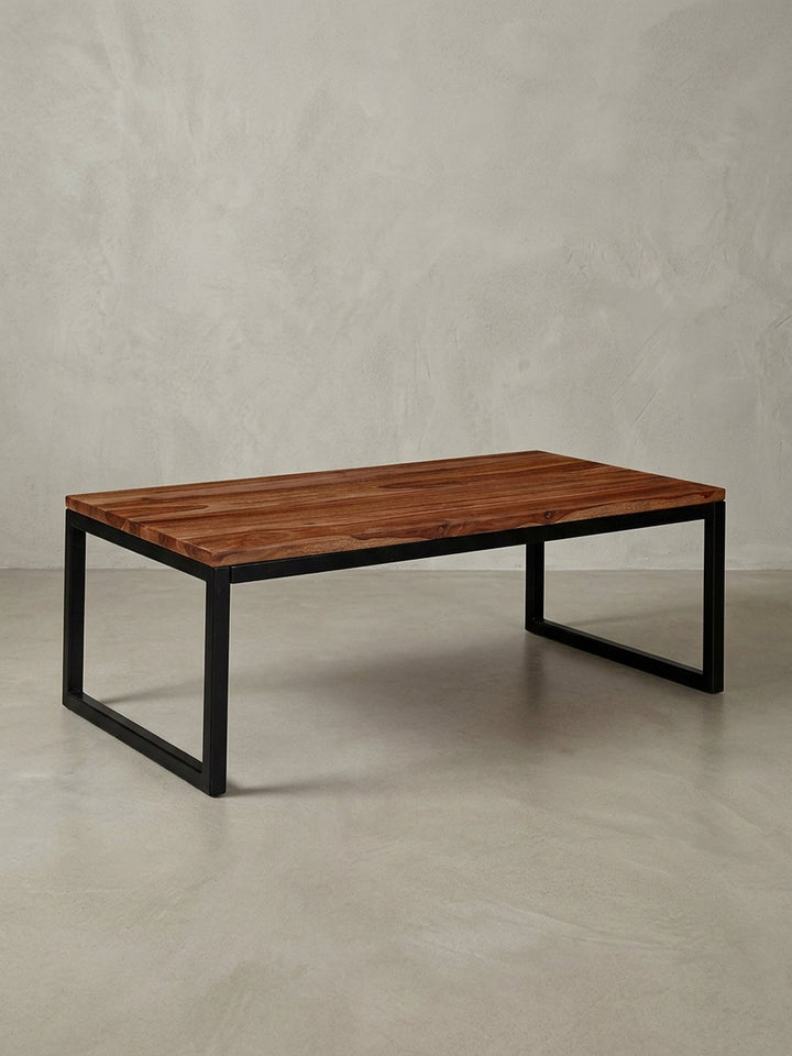 Freigestellter Couchtisch im Industrial Design mit Tischplatte aus massivem Sheesham-Holz und schwarzen Metallbeinen, Frontalansicht._