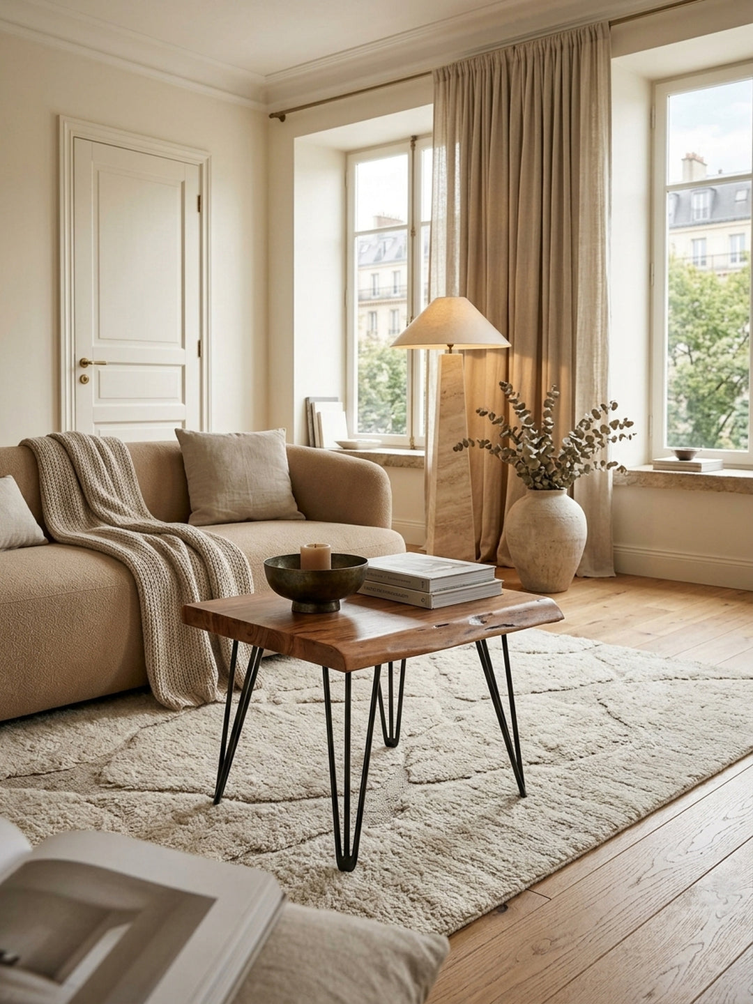Eleganter Couchtisch aus Sheesham Massivholz mit organischer Baumkante im luxuriösen Wohnzimmer. Warme Holztöne und schwarze Hairpin-Legs harmonieren mit hellem Teppich._