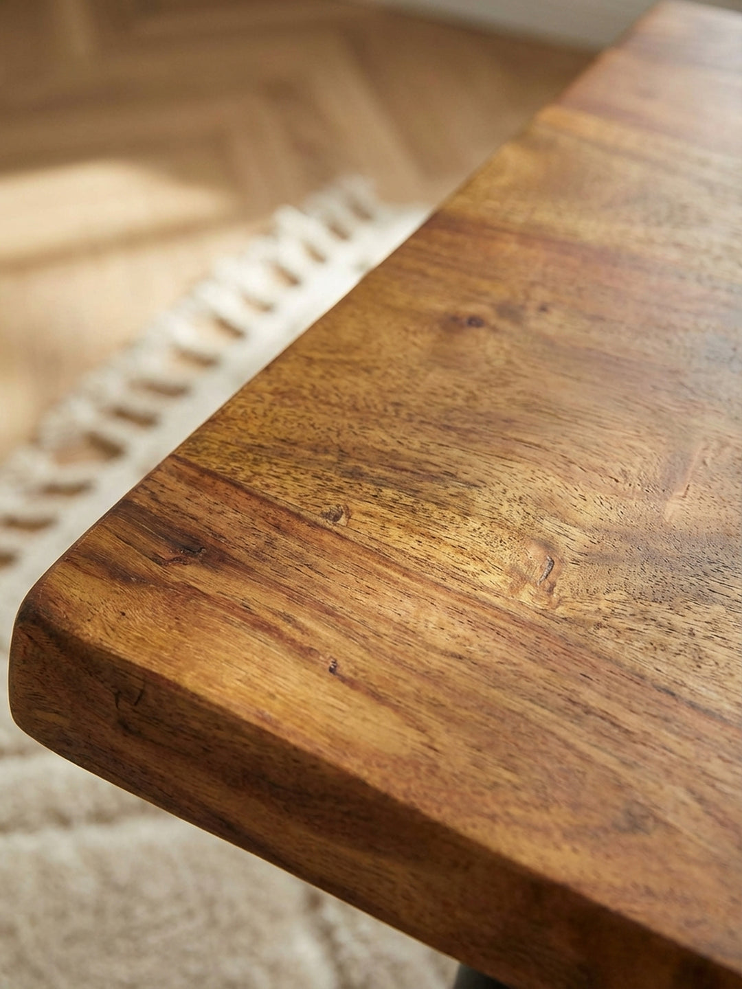 Detailaufnahme der lebendigen Maserung und der natürlichen Baumkante des Massivholz-Couchtischs, die Handwerkskunst und Qualität zeigt._