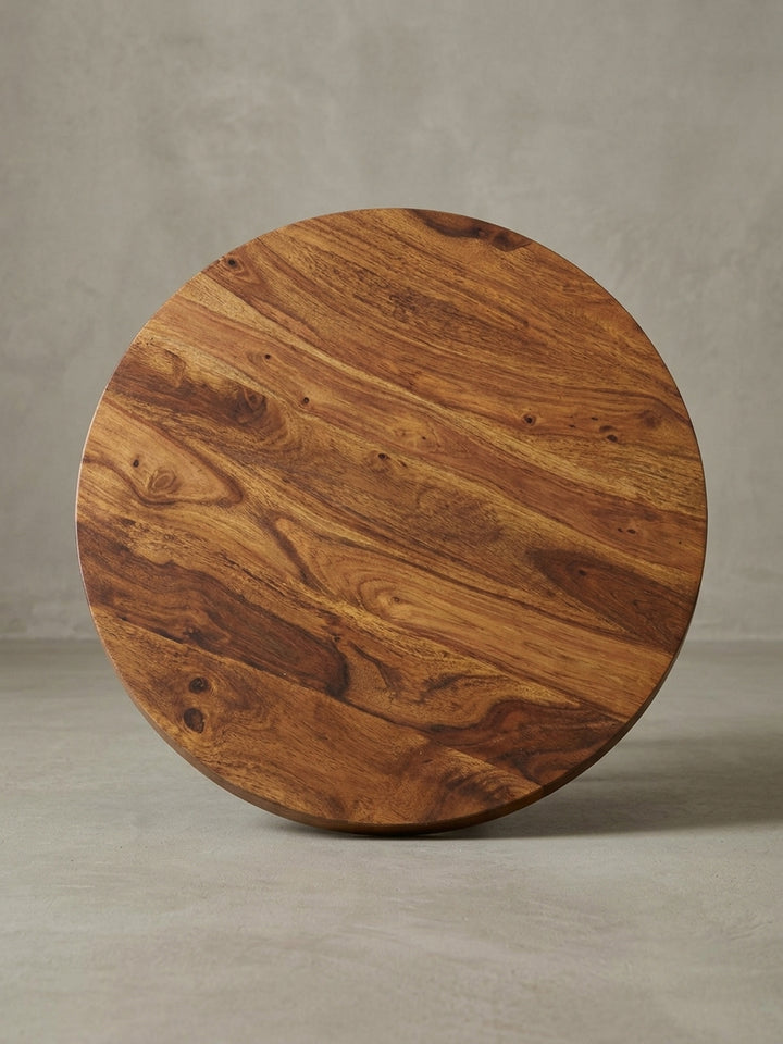 Alternativer Blickwinkel auf den runden Kaffeetisch, der die dynamische Holzmaserung der Sheesham-Platte und das moderne Design des schwarzen Metallgestells hervorhebt._