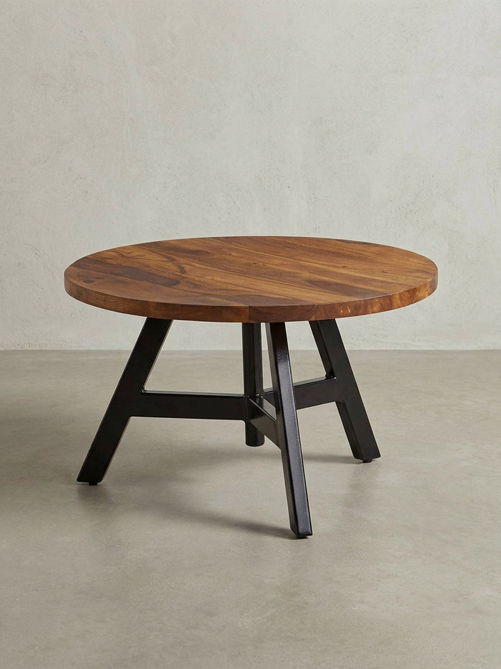 Freigestellter runder Couchtisch 60 cm Durchmesser, Frontansicht zeigt die Tischplatte aus Sheesham Massivholz auf dem stabilen, dreibeinigen Metallgestell in Schwarz._