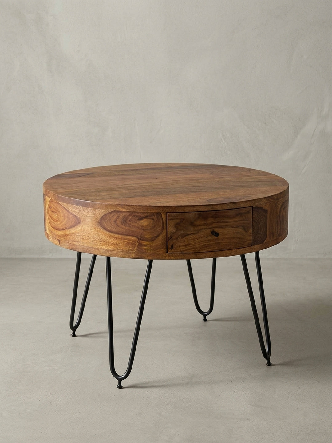 Runder Couchtisch Sheesham Massivholz auf weißem Hintergrund. Der kompakte Wohnzimmertisch besticht durch seinen zylindrischen Korpus und die feinen schwarzen Metallbeine._