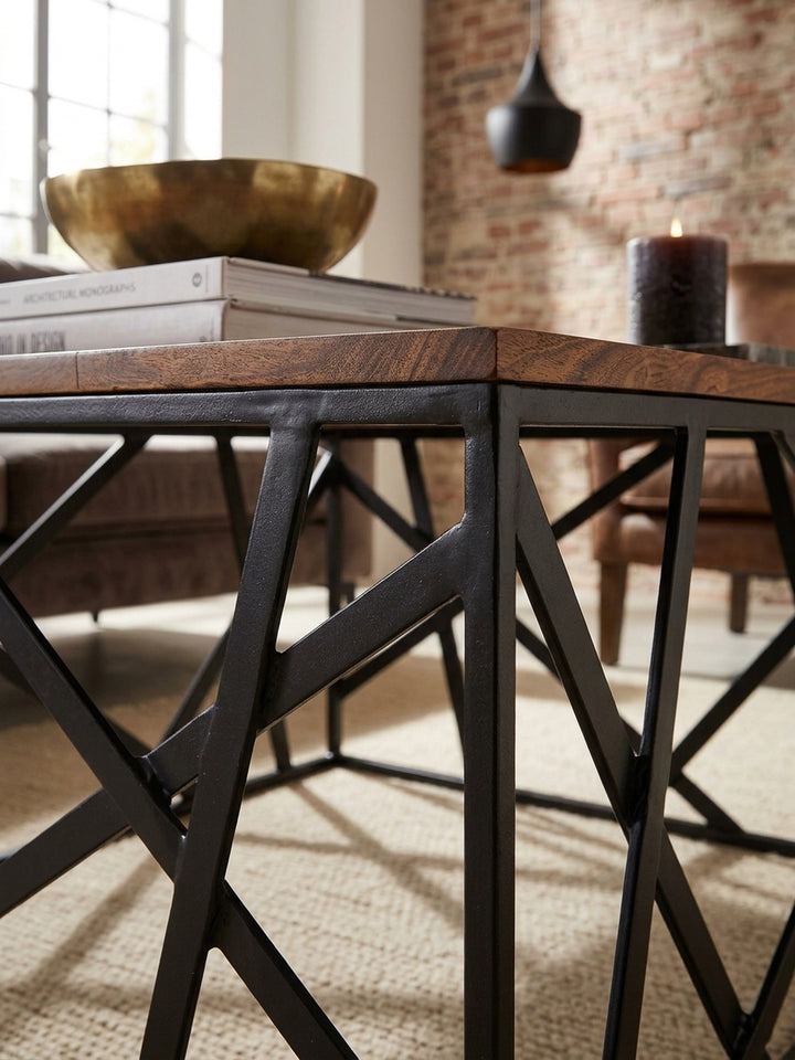 Detailaufnahme der Couchtisch-Oberfläche. Die markante, naturbelassene Holzmaserung des braunen Sheeshamholzes trifft direkt auf die matt schwarz lackierten Eisenstreben des Designertisches._