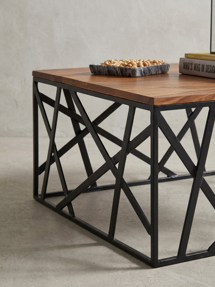 Nahaufnahme der Materialverbindung am Kaffeetisch. Der fließende Übergang von der warmen, klarlackierten Naturholzplatte zum kühlen, schwarzen Eisengestell zeigt die präzise Verarbeitung._