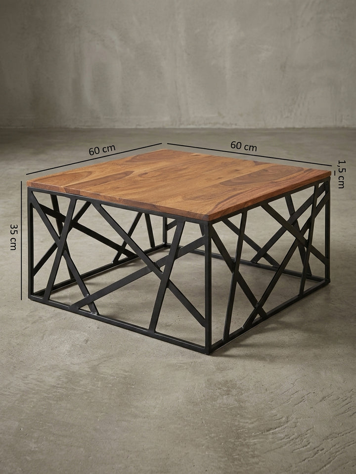 Rückwärtige Detailansicht des Industrial Couchtisches. Die hochwertigen Schweißnähte des schwarzen Metallgestells stützen die massive Holzplatte aus dunklem Sheesham dauerhaft und sicher._