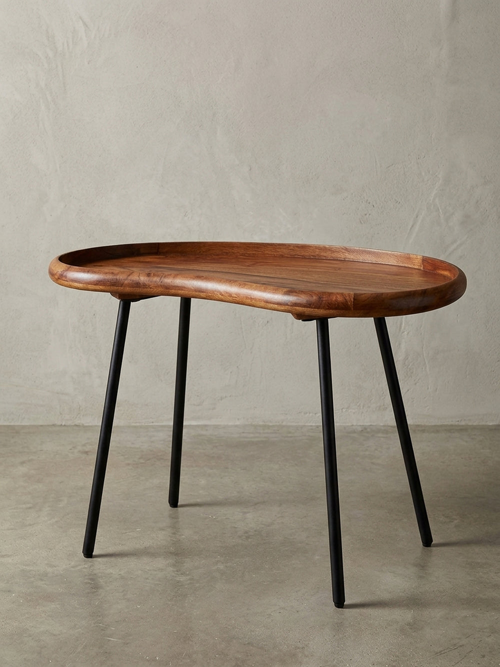 Kleiner Nierentisch aus massivem Sheesham-Holz mit schwarzen Metallbeinen. Der 71 cm breite Couchtisch im 50er Jahre Retro-Look präsentiert sich freigestellt vor weißem Hintergrund._