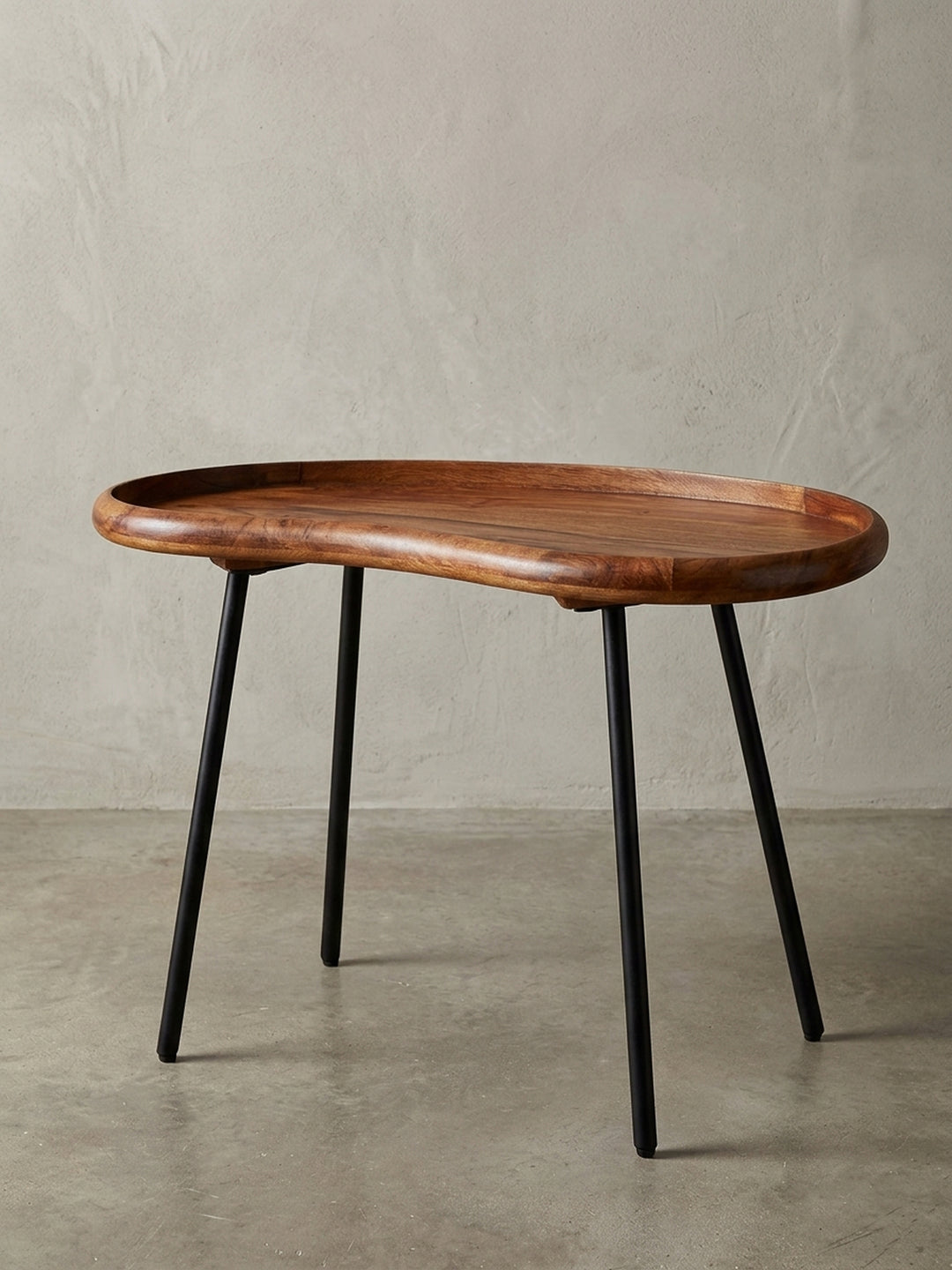Kleiner Nierentisch aus massivem Sheesham-Holz mit schwarzen Metallbeinen. Der 71 cm breite Couchtisch im 50er Jahre Retro-Look präsentiert sich freigestellt vor weißem Hintergrund._